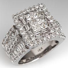 This stunning ring is centered with six (6) invisible/prong set princess cut diamonds surrounded by ten (10) prong set baguette cut diamonds and thirty (30) prong set round, brilliant cut diamonds. The shoulders of the ring each contain ten (10) channel set baguette cut diamonds and fifteen (15) prong set, round diamonds. The ring measures 14.8mm at the top, rises 10.0mm above the finger, tapering to 5.9mm wide and 1.8mm thick at the base of the shank. It is currently a size 6. Platinum Cluster Diamond Ring With Baguette Diamonds, Dazzling Diamond White Ring With Square Cut, Dazzling Square-cut Diamond Ring With Accents, Dazzling Square Cut Diamond Ring With Accents, Dazzling Square-cut Diamond Ring, Classic Cluster Diamond Ring With Baguette Diamonds, Square Cut Diamond Ring With Halo Setting For Anniversary, Square Cut Diamond White Ring, Dazzling Square Cut Diamond Ring For Wedding