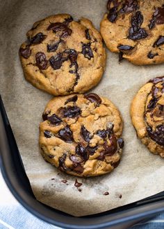 four chocolate chip cookies sitting on top of a pan