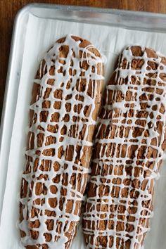 two cookies with icing sitting on top of a white tray next to each other