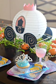 a table topped with plates filled with cupcakes next to an orange and white paper lantern