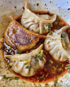 some dumplings are sitting in a bowl with sauce