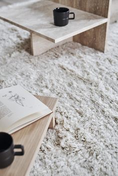 a coffee table sitting on top of a white rug next to a book and cup