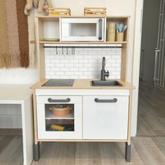 a toy kitchen with white cabinets and wooden floors