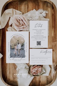 the wedding stationery is laid out on a wooden tray