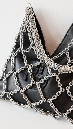 a black purse with silver chains hanging from it's front and back sides, on a white surface