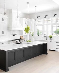 a large kitchen with white cabinets and black island