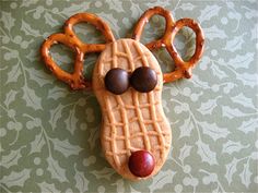 a cookie shaped like a reindeer's head with pretzels on its nose