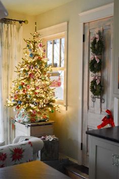 a decorated christmas tree sitting in the corner of a living room next to a window