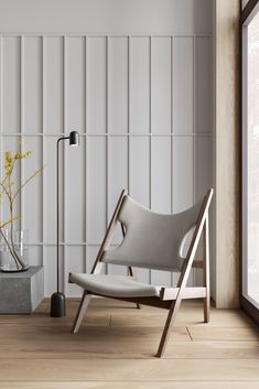 a white chair sitting on top of a hard wood floor next to a vase filled with flowers