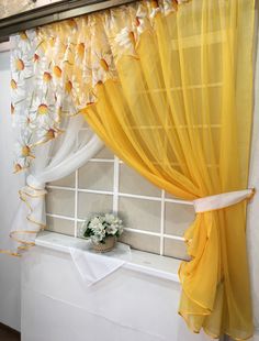 the window is decorated with yellow and white curtains, along with a flower pot in front of it