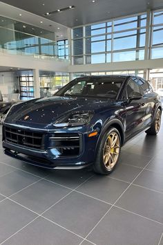 a blue porsche cayen is parked in a showroom