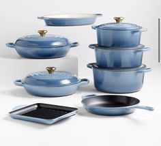 blue pots and pans with gold handles on white background, including one holding a casserole