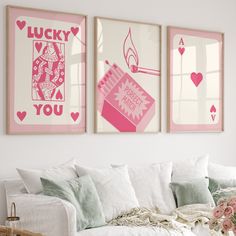 three pink and white posters hanging on the wall above a couch in a living room