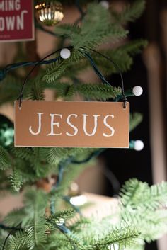 a wooden sign hanging from the side of a christmas tree that says jesus on it