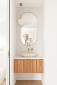 a bathroom with a round mirror above the sink and wooden cabinetry on the wall