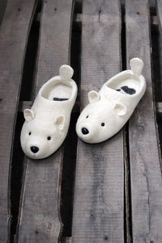 a pair of white slippers sitting on top of a wooden floor next to a bear head