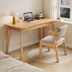 a laptop computer sitting on top of a wooden desk next to a chair and window