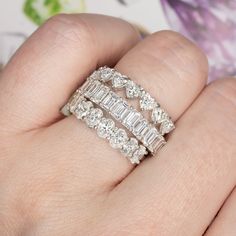 a woman's hand with three rings on top of it and one is holding the other