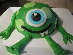 a green frog cake sitting on top of a white plate with blue and black eyes