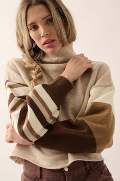 a woman wearing a turtle neck sweater and brown pants with her arms crossed looking at the camera