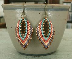 a pair of colorful beaded earrings sitting on top of a bowl