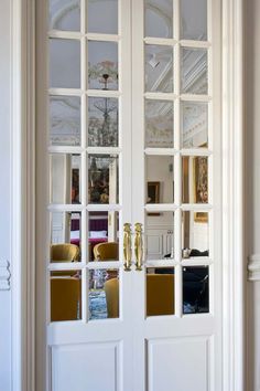 two white doors with mirrored glass panels in the middle and one has a yellow chair