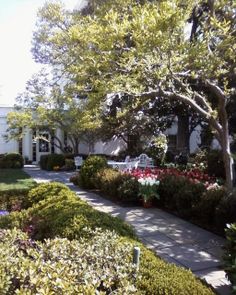 a white house surrounded by trees and flowers