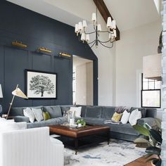 a living room filled with lots of furniture and a chandelier hanging from the ceiling