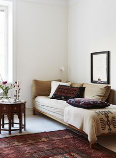 a living room with a couch, rug and table in front of a window on the wall