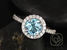 a blue diamond ring sitting on top of a black rock with white diamonds around it