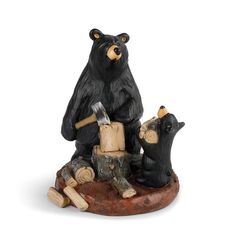 a figurine of two bears sitting on a log with an ax in their hands