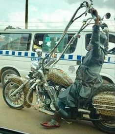 a man on a motorcycle with his hand up in the air and other vehicles behind him