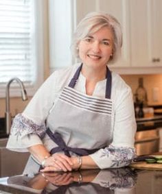 a woman in an apron sitting at a kitchen counter