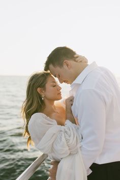 a man and woman standing next to each other on a boat in the water with their arms around each other