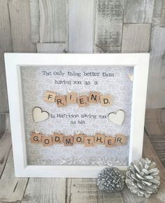 a wooden scrabble frame with the words friend and two pine cones