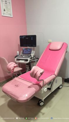 a pink reclining chair sitting in a room next to a laptop computer on a desk