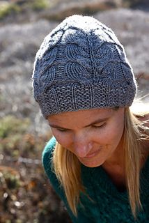 a woman wearing a knitted hat looking down at her cell phone