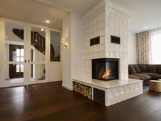 a living room with a fire place in the center and wood flooring on the other side