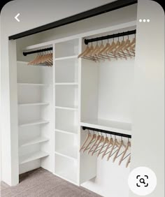 an empty closet with white shelves and wooden clothes hangers on the wall, along with carpeted flooring