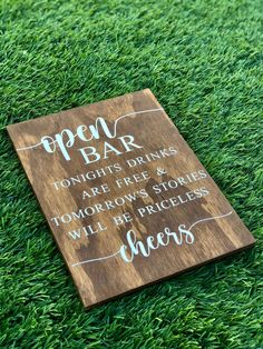 a wooden sign that says open bar on the grass