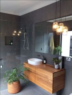 a bathroom with a sink, mirror and plants in the shower stall next to it