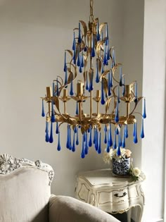 a chandelier hanging from the ceiling in a living room with blue glass drops