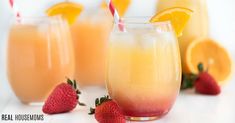 three glasses filled with orange juice and strawberries next to each other on a white surface