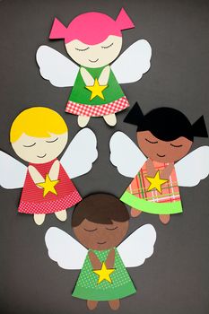 paper cut outs with angels and stars in the shape of children's faces on a gray background