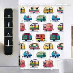 a bathroom with a shower curtain that has different colored campers on it and a toilet in the background