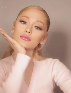 the woman is posing with her hand on her chin and looking at the camera while wearing a pink sweater