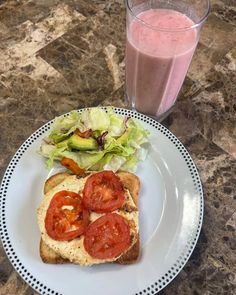 a sandwich with tomatoes, lettuce and tomato slices on it next to a glass of juice