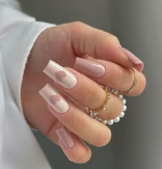 a woman's hand with pink and white manicures on it, holding pearls