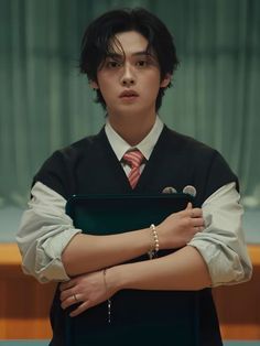 a young man in a suit and tie holding a laptop computer with his arms crossed