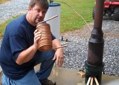 a man kneeling down next to a propane heater and holding a large cup